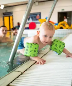 Lille dreng med badevinger ved pool